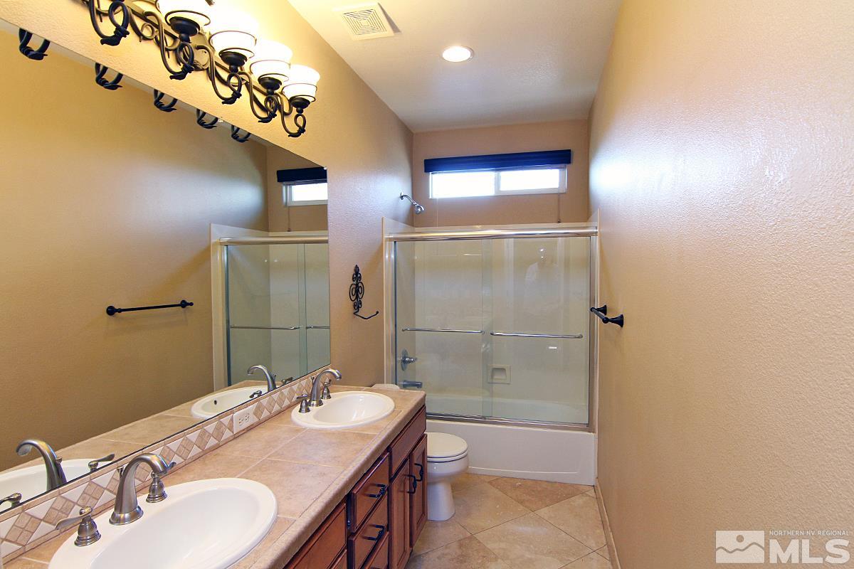 11205 Messina Way Reno, NV 89521 - Photo 26 of 40 a bathroom with a granite countertop sink a mirror and shower