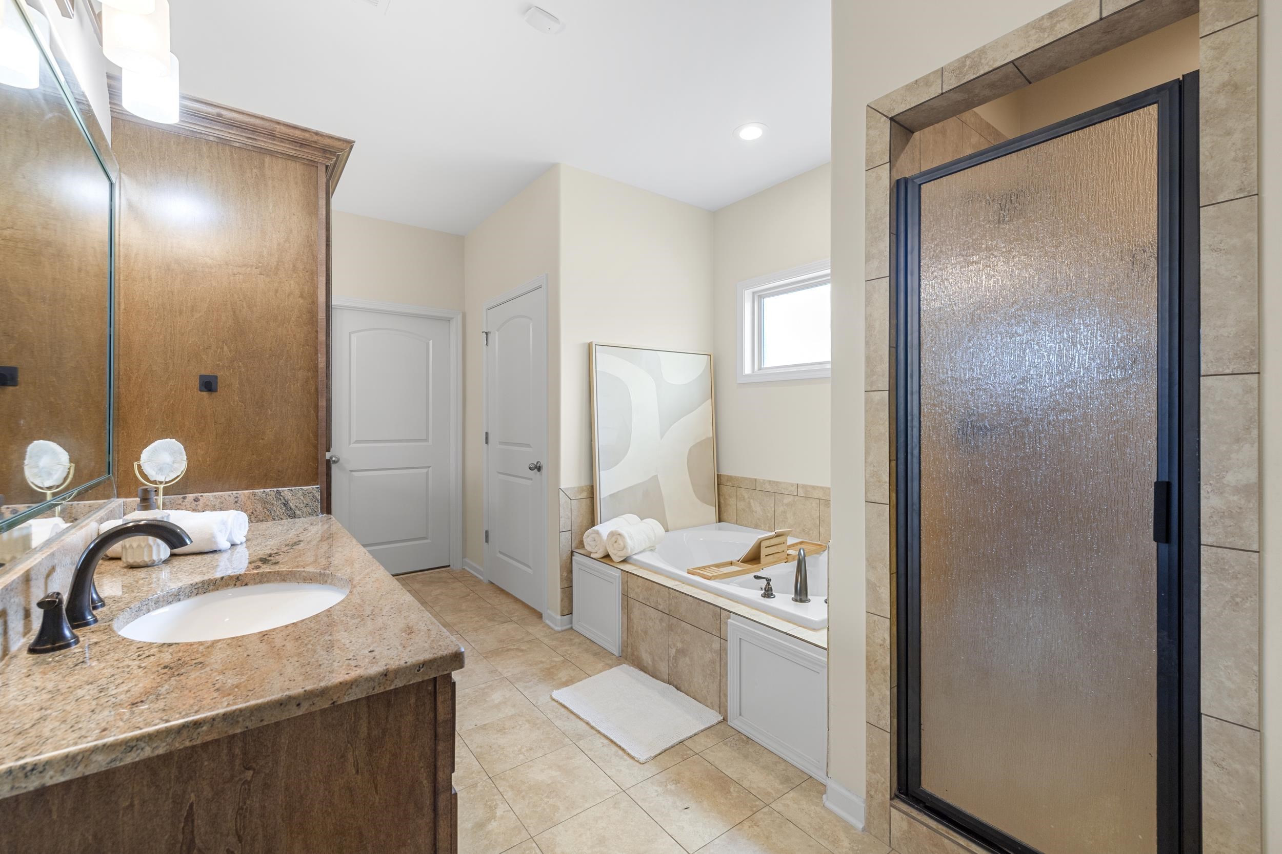 185 Belmont Road Mason, TN 38049 - Photo 16 of 38 Bathroom featuring a vanity with a granite countertop and undermount sink, a built-in soaking tub with tile surround, a separate shower with a textured glass door, and recessed lighting