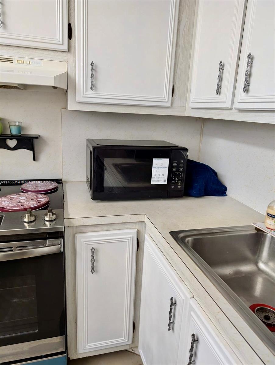 Boynton Beach Boynton Beach, FL 33435 - Photo 23 of 29 a kitchen with granite countertop white cabinets and a stove