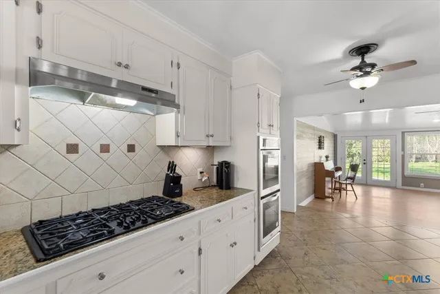 a kitchen with stainless steel appliances granite countertop a stove a sink a refrigerator and white cabinets