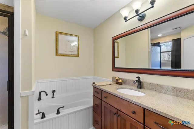 a bathroom with a granite countertop sink mirror and bathtub