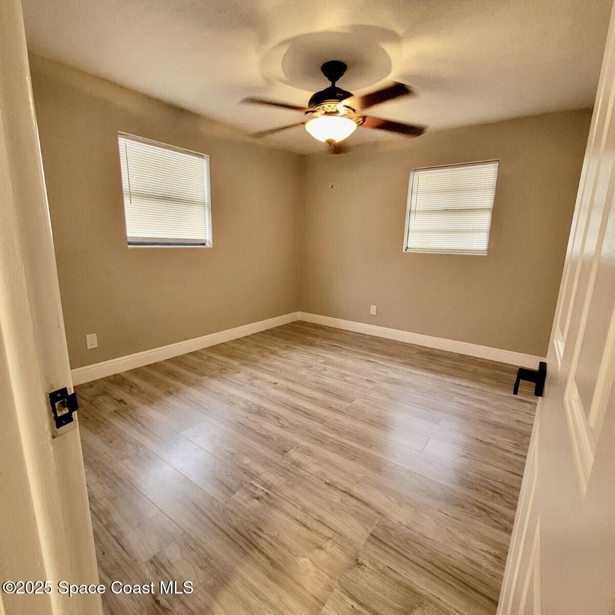 1510 Cambridge Drive Cocoa, FL 32922 - Photo 7 of 19 an empty room with wooden floor fan and windows