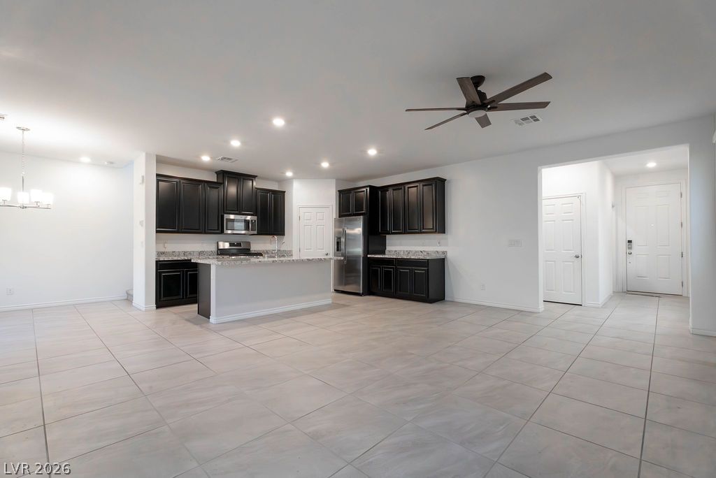 7126 Calvert Cliffs Street North Las Vegas, NV 89084 - Photo 4 of 44 A contemporary kitchen and living area featuring dark cabinetry, stainless steel appliances, and sleek tiled flooring.