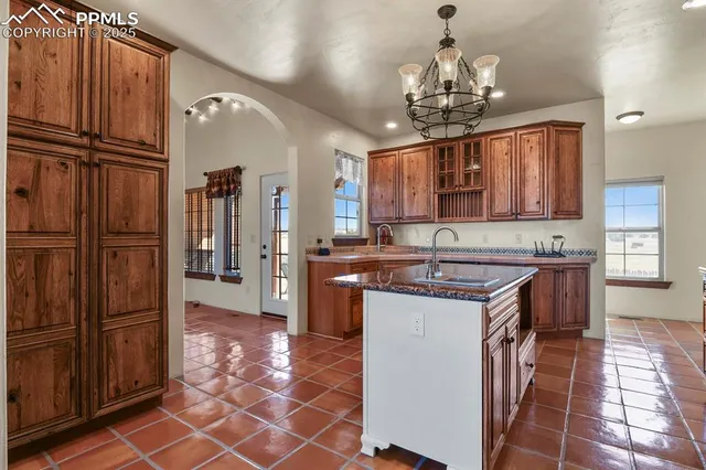 a kitchen with kitchen island granite countertop a refrigerator and a sink