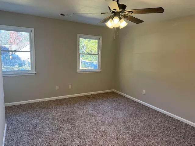 an empty room with windows and fan