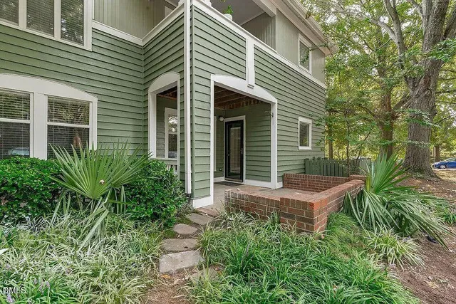 a view of a house with a yard and wooden bench