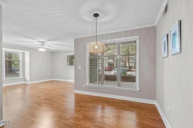 a view of an empty room with window and wooden floor