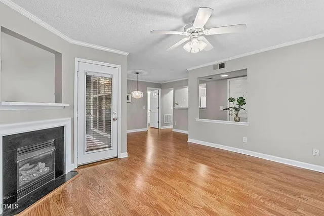 a view of an empty room with chandelier fan and wooden floor