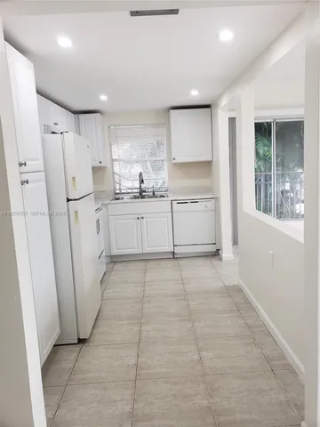 a room with white cabinets and refrigerator