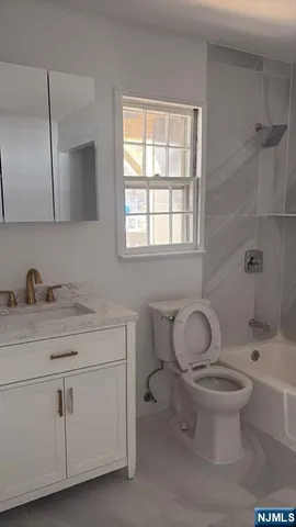 a bathroom with a granite countertop toilet sink and mirror