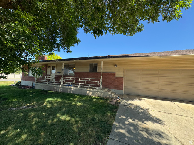 1611 South 75 East Bountiful, UT 84010 - Photo 3 of 6 Front exterior featuring a brick facade, beige horizontal siding, an attached garage, a covered front porch, and a concrete driveway