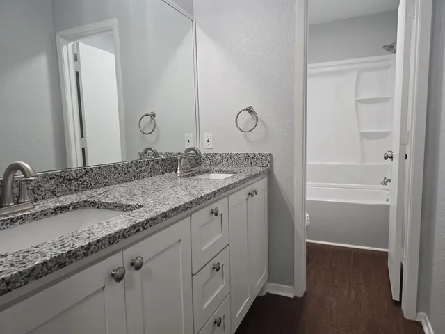 a bathroom with a granite countertop sink double and mirror