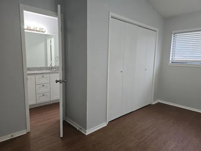 an empty room with wooden floor closet and windows