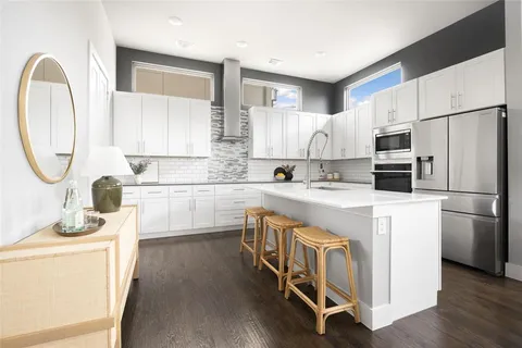 a kitchen with stainless steel appliances granite countertop a stove a sink dishwasher a refrigerator and a microwave oven with wooden floor