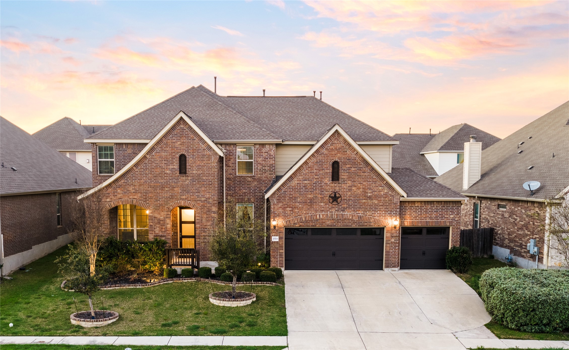 Traditional-style house with an attached garage, driveway, a lawn, brick siding, and roof with shingles
