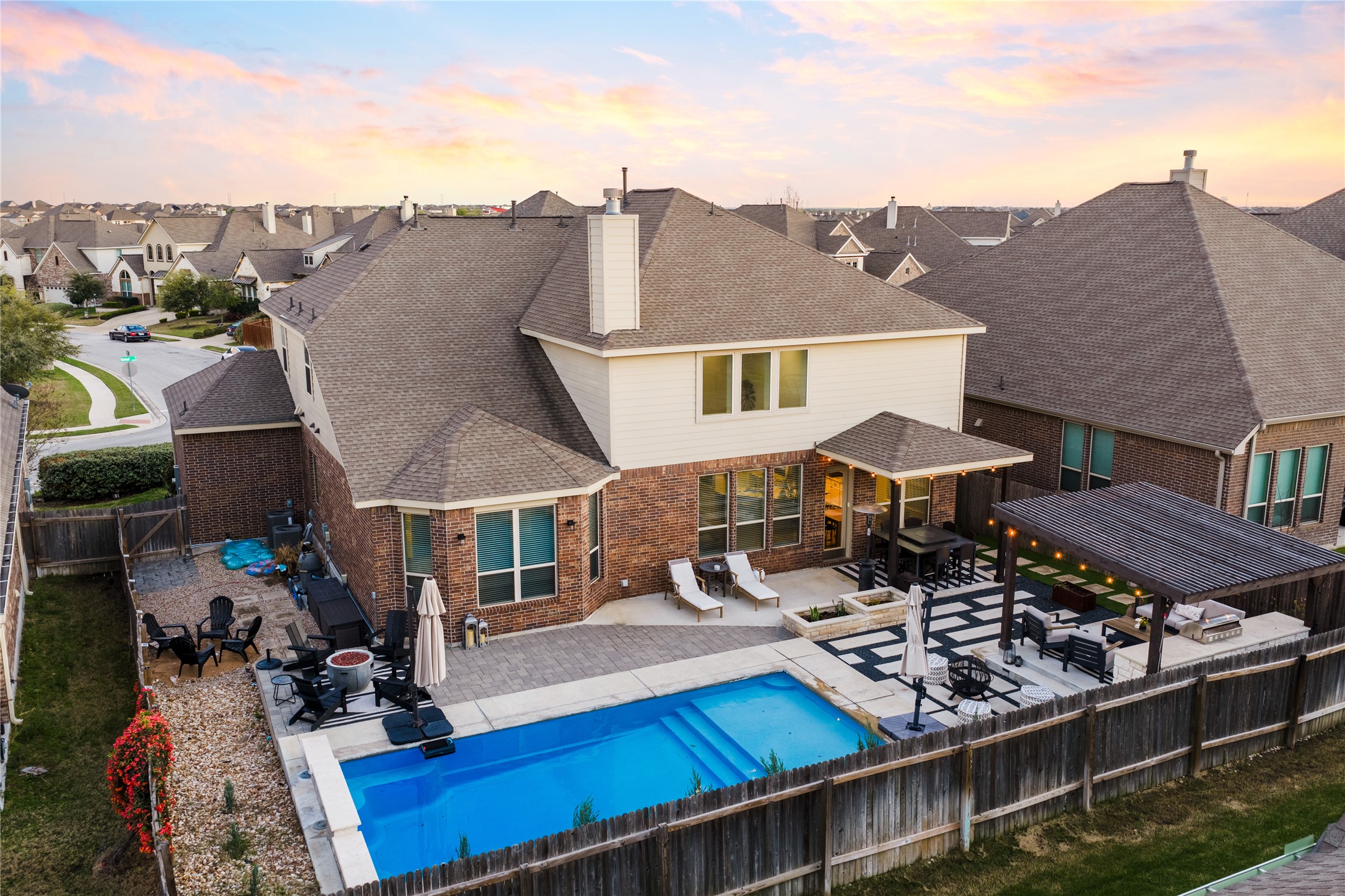 20524 Fairleaf Street Pflugerville, TX 78660 - Photo 32 of 35 Back of house at dusk featuring a patio, a fenced backyard, roof with shingles, and brick siding