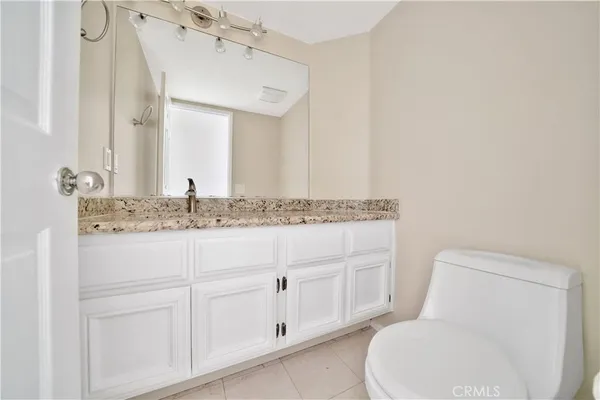 a bathroom with a granite countertop toilet sink and mirror
