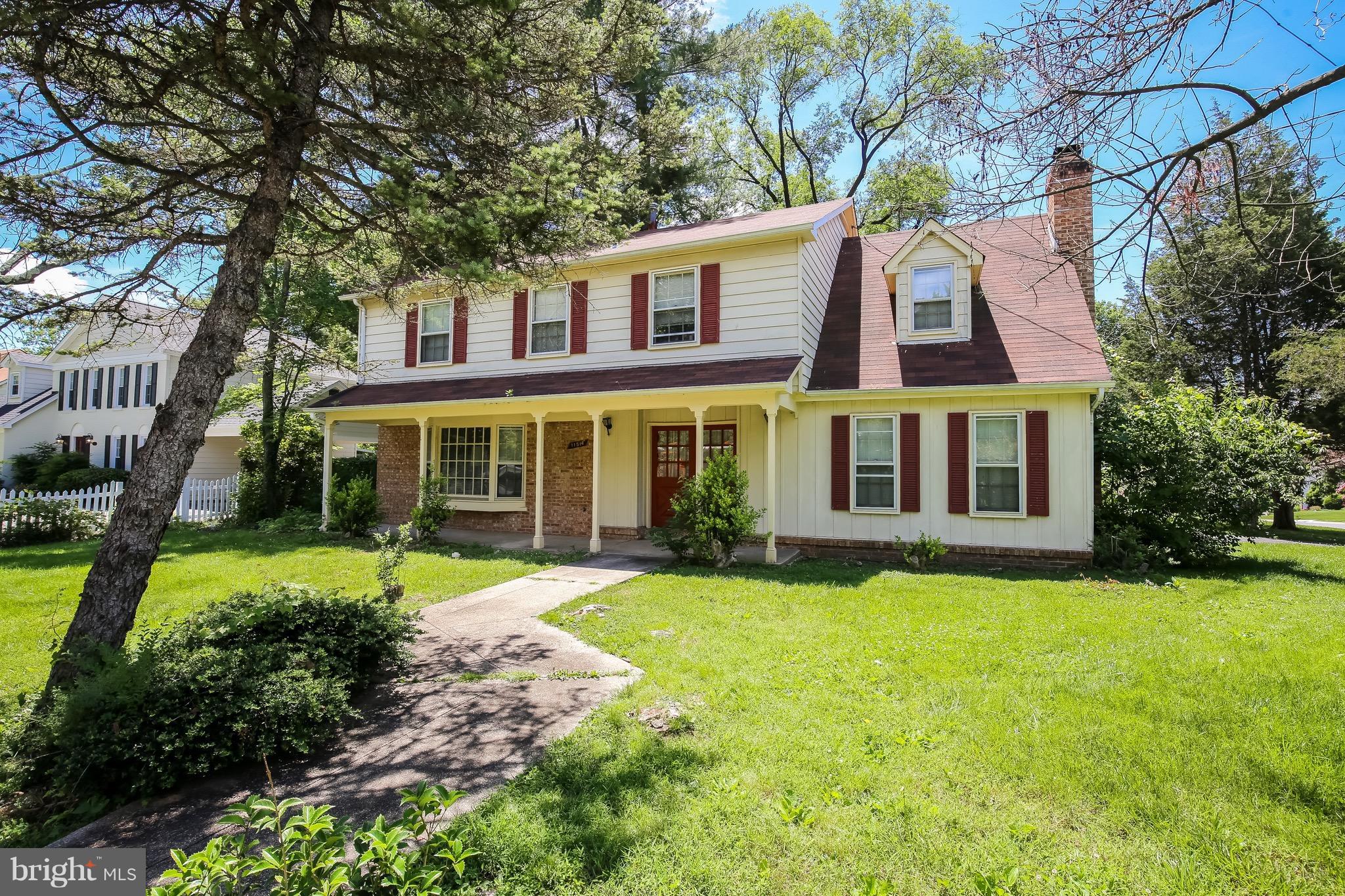 11514 Seven Locks Road Rockville, MD 20854 - Photo 2 of 10 a view of a brick building next to a yard with potted plants and large trees