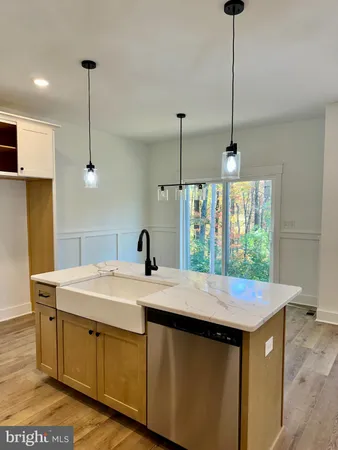 a kitchen with a stove a sink a chandelier and wooden floor