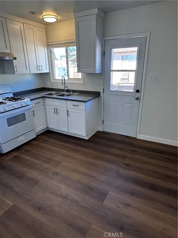 a kitchen with granite countertop wooden floors stainless steel appliances and window