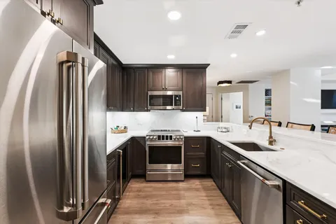 a kitchen with stainless steel appliances granite countertop a sink stove and refrigerator