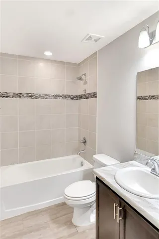 a bathroom with a granite countertop sink a toilet and bathtub