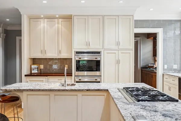 a kitchen with granite countertop a sink stainless steel appliances and white cabinets