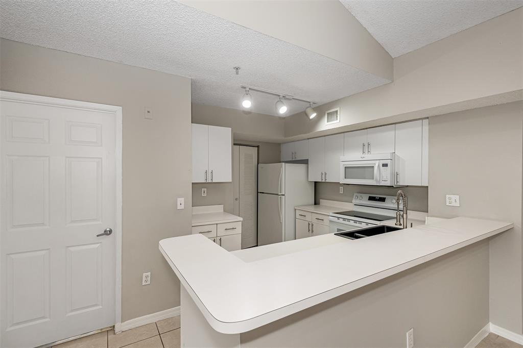 3848 Lyons Road, Unit 202 Coconut Creek, FL 33073 - Photo 11 of 32 a kitchen that has a lot of white cabinets and stainless steel appliances