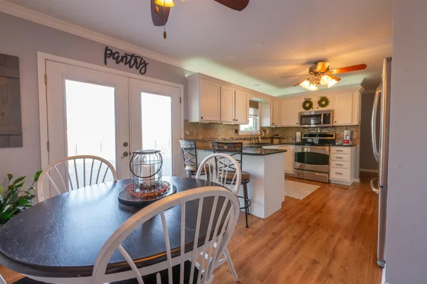 a kitchen with kitchen island a dining table chairs stainless steel appliances and cabinets