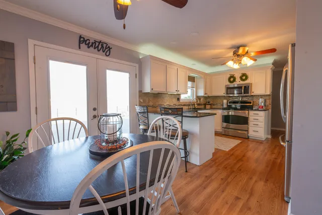 a kitchen with kitchen island a dining table chairs stainless steel appliances and cabinets