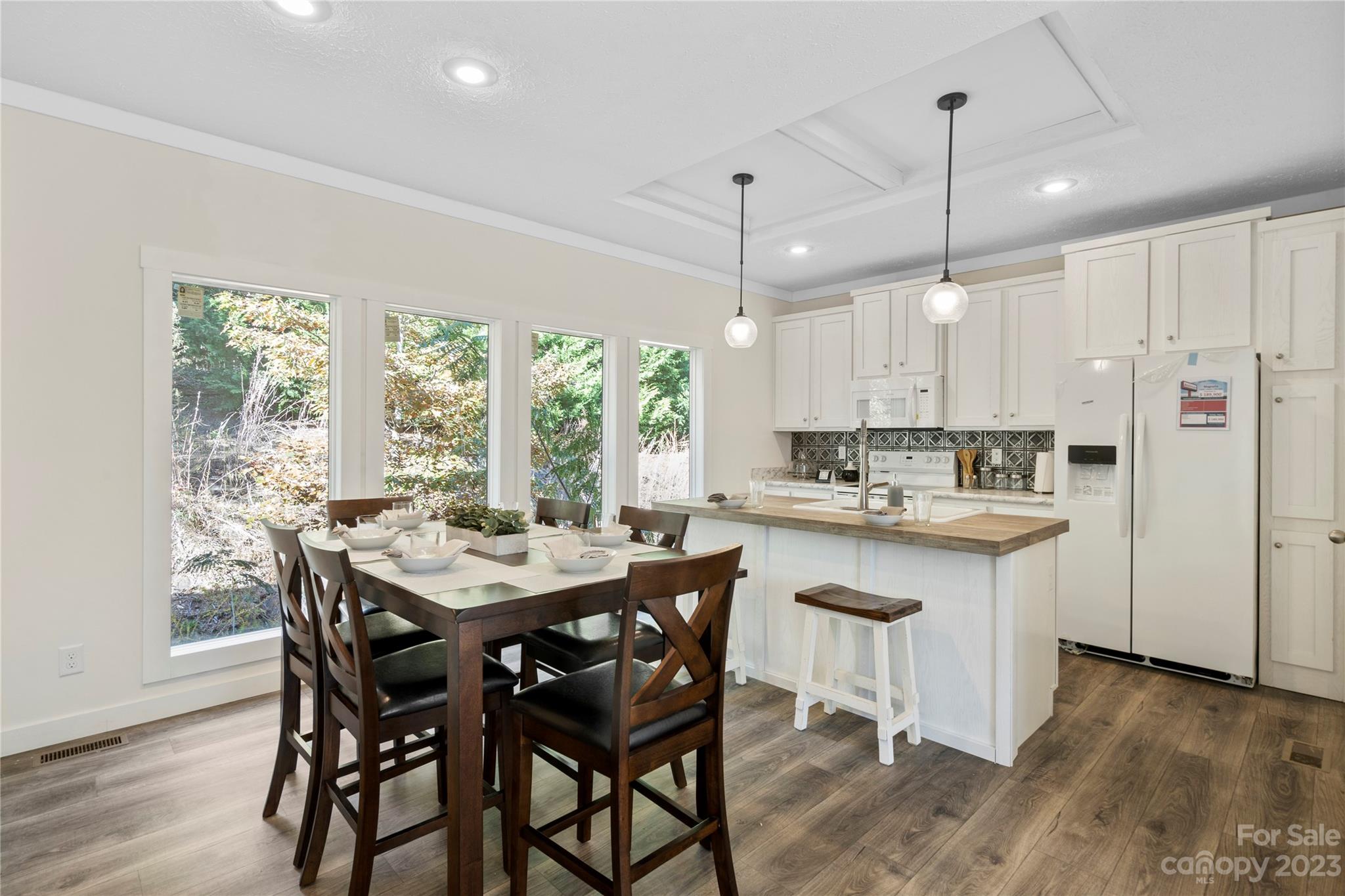 a kitchen with kitchen island a dining table chairs and white cabinets
