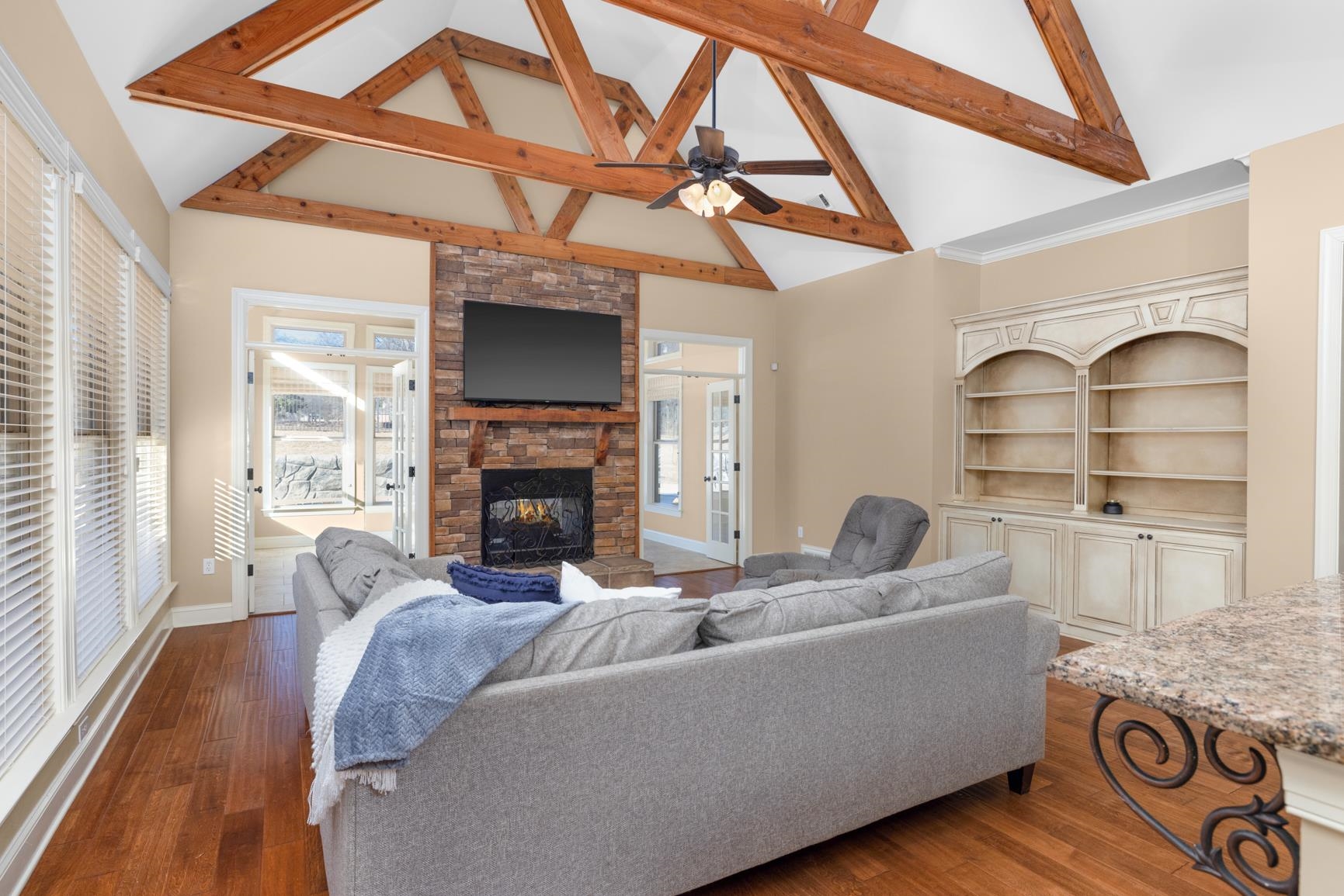 Living area featuring a stone fireplace, wood finished floors, and ceiling fan
