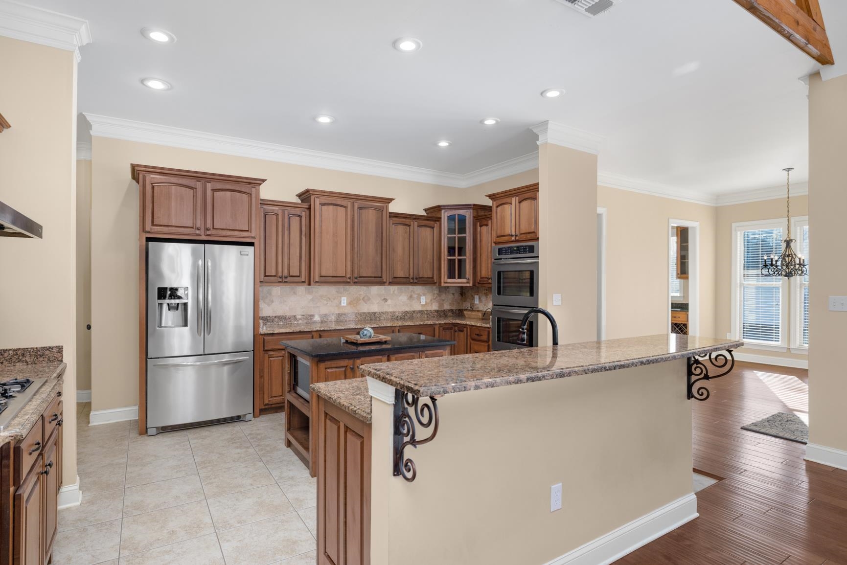 104 Eagle Trace Road Covington, TN 38019 - Photo 4 of 40 Kitchen featuring wood finish cabinetry, a kitchen island with sink, stainless steel appliances, a breakfast bar, and glass insert cabinets