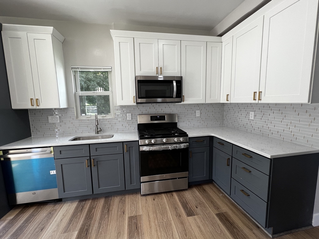 56 Pelham Street Methuen, MA 01844 - Photo 2 of 27 a kitchen with wooden cabinets and a stove top oven