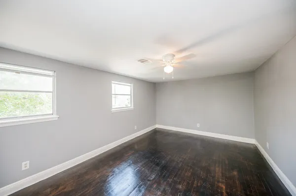 an empty room with wooden floor and windows