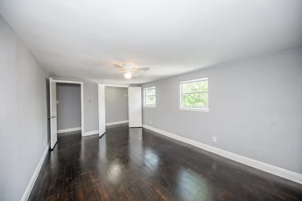 an empty room with wooden floor and windows