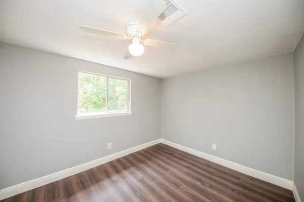 an empty room with a window and wooden floor