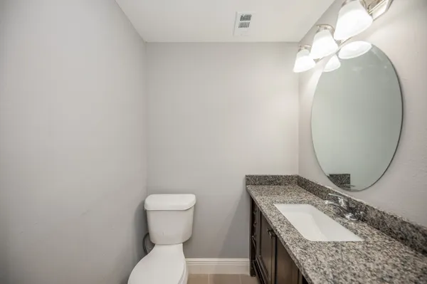 a bathroom with a granite countertop sink mirror vanity and toilet