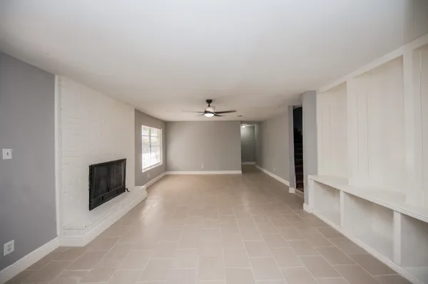 an empty room with windows and fireplace