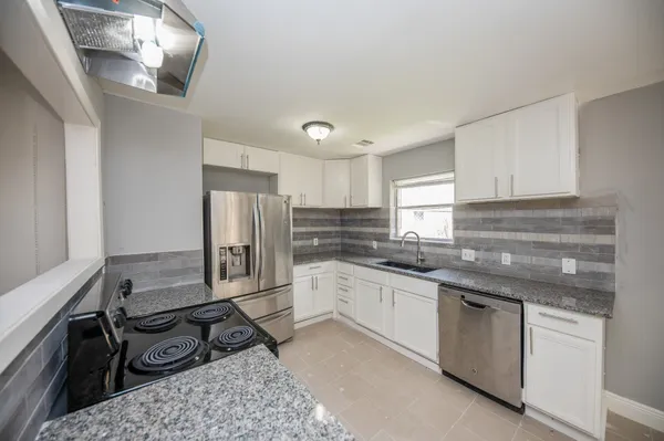 a kitchen with stainless steel appliances granite countertop a sink stove refrigerator and cabinets