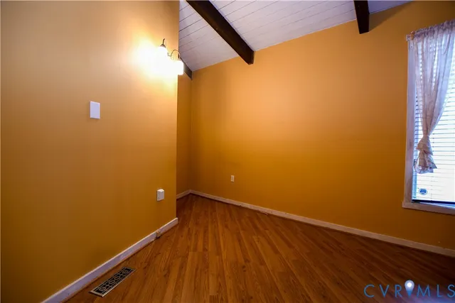 a view of a room with wooden floor and small window