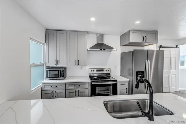 a kitchen with stainless steel appliances a stove a sink a refrigerator a counter space and cabinets