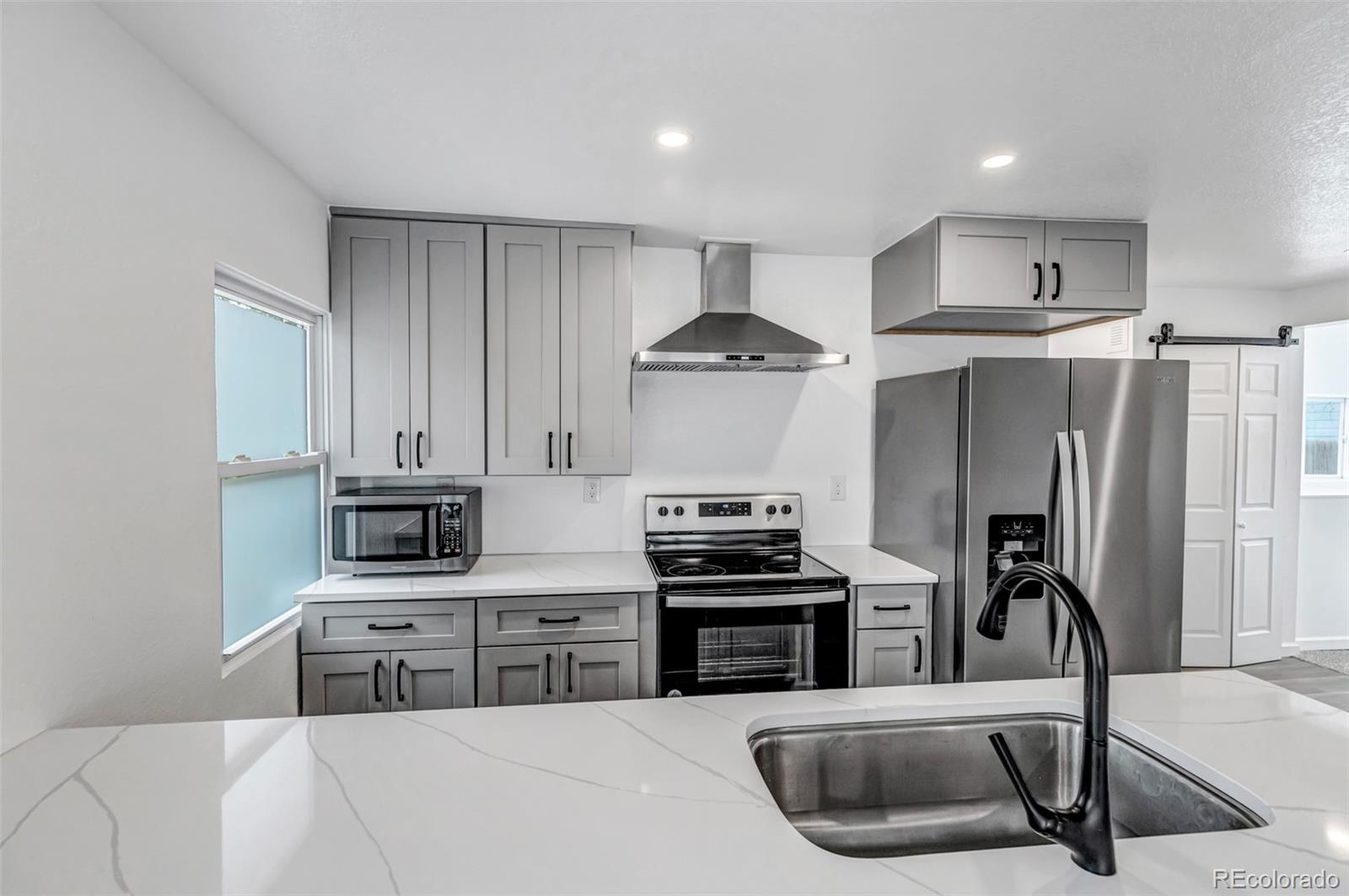 10 South Irving Street Denver, CO 80219 - Photo 14 of 35 a kitchen with stainless steel appliances a stove a sink a refrigerator a counter space and cabinets