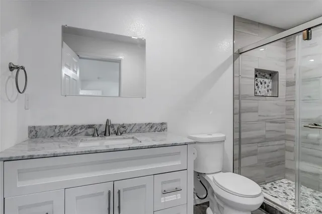 a bathroom with a granite countertop toilet sink and a mirror