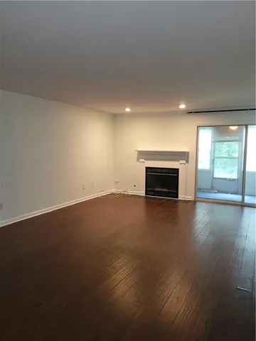 an empty room with windows fireplace and wooden floor