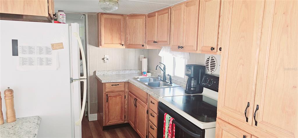 10315 Cortez Road West, Unit 714 Bradenton, FL 34210 - Photo 15 of 26 a kitchen with stainless steel appliances granite countertop a refrigerator a sink dishwasher and white cabinets with wooden floor