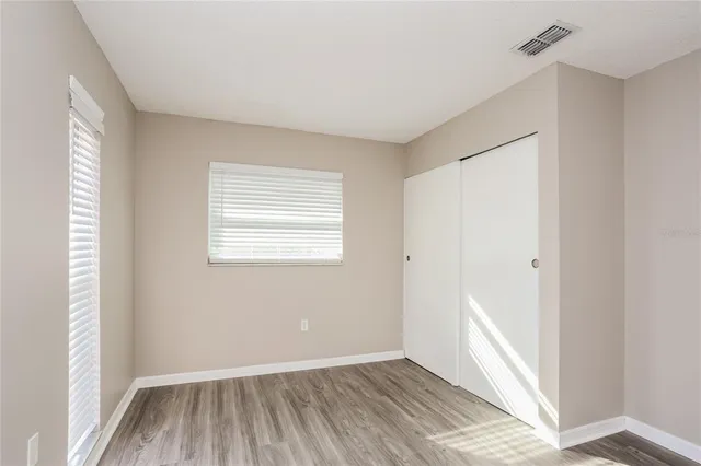 a view of an empty room with wooden floor and a window