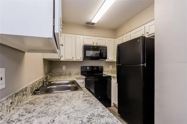 a kitchen with granite countertop a refrigerator and a sink