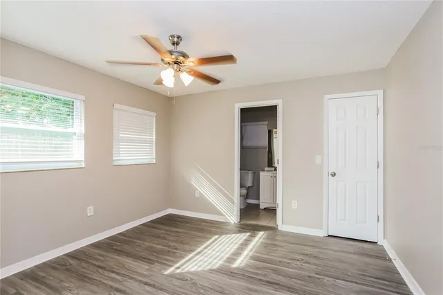 a view of empty room with wooden floor and fan