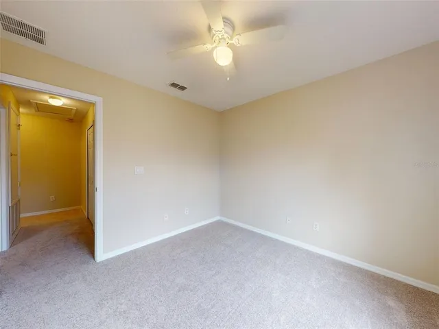 an empty room with a fan & a ceiling fan